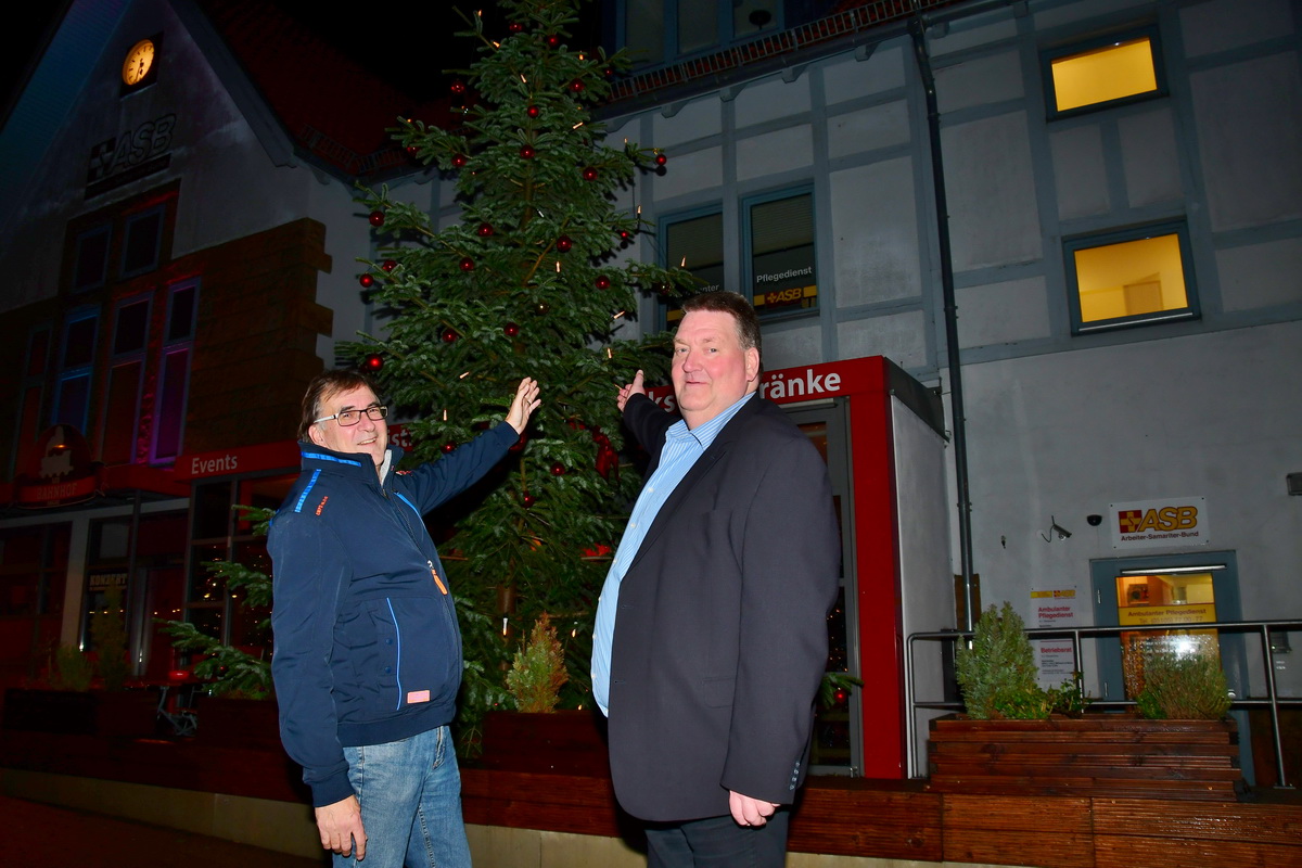 Jens Meier (rechts) und Klaus Fricke vom ASB freuen sich über den kerzengeraden und schönen geschmückten Baum vor dem ASB-Bahnhof